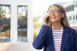 Good business talk. Portrait of cheerful mature business woman wearing eyeglasses and classic wear talking on mobile phone and smiling while standing against office building outdoors