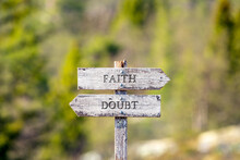 Faith Doubt Text Carved On Wooden Signpost Outdoors In Nature. Green Soft Forest Bokeh In The Background.