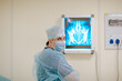 © Alina - Adult white doctor posing near the x-rayed at the white operation room. Copy space.