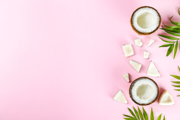 Wall Mural - Top view shot of coconuts, whole and cracked on halves on paper textured background with a lot of copy space for text. Background with raw fruit of tropical palm. Flat lay.