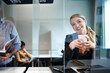 © Marc Zimmermann - Portrait of smiling young blond businesswoman holding cup while standing by colleague in office seen through glass shield