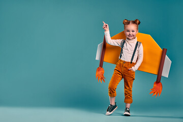 beautiful little child girl with homemade cardboard plane wings, imagination and girl power concept