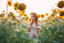 Beautiful Young Woman Standing In Flowering Field. Yellow Flowers Sunflower. Blonde Hair, Hairstyle Two Braids. Girl In Hat Enjoys Summer Nature. Art Healthy Lifestyle Concept. Backdrop Green Leaves
