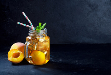 Wall Mural - Peach ice tea drink on dark background with mint and ice