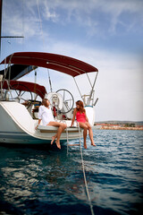 Wall Mural - Young girls sitting on stern of a yacht