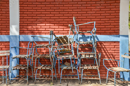 Pile of broken chairs outside a classroom in a public school class in Nicaragua with a red brick wall. Equipment in poor condition, without students. Concept for education in developing countries