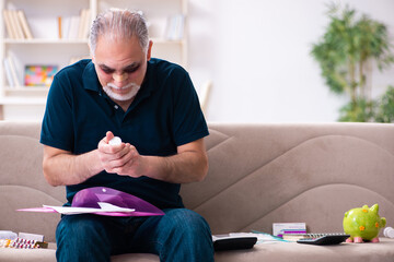 Wall Mural - Old injured man in budget planning concept