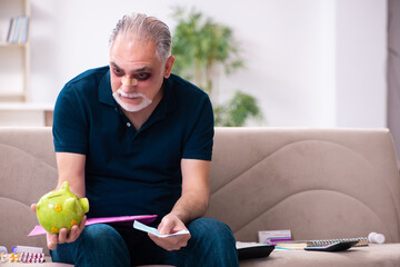 Wall Mural - Old injured man in budget planning concept