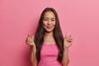 Young Asian brunette woman poses with menstrual cup, shows how to use, gives recommendations, makes korean like sign, isolated on pink wall. Women health, zero waste alternative and gynecology