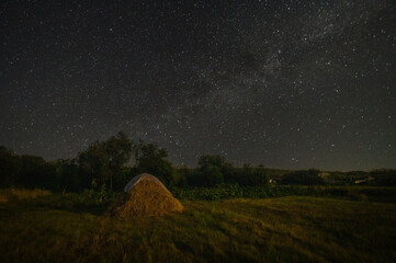 a haystack under a dark starry night sky