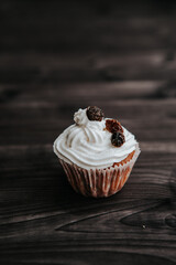 Wall Mural - muffin with cream and raisins on a dark wooden background