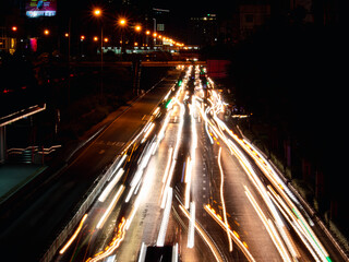 Long exposure light trails on the street at night, motion speed traffic light with blurred traces from cars on road