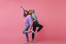 Full-length Photo Of Inspired Girls Funny Dancing Together. Indoor Shot Of Cheerful Best Friends Standing On Bright Background.