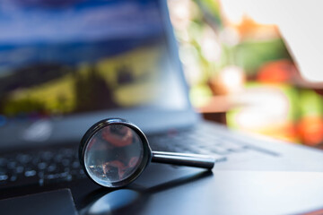 Magnifying glass on laptop computers keyboard, shallow depth of field, copy space.