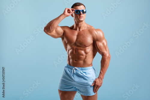 Foto Handsome muscular man naked torso abs, isolated on blue background