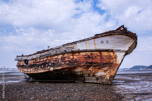 Abandoned and scrapped wooden fishing vessel lying on the beach.