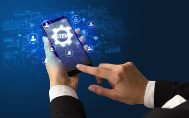female hand holding smartphone with stem abbreviation, modern technology concept