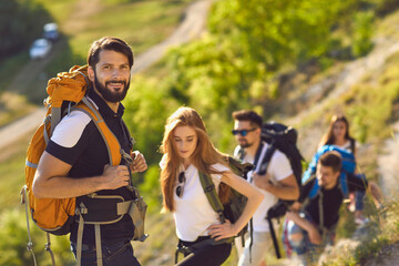 Wall Mural - male backpacker with his friends climbing to mountain top. team of hikers mountaineering on summer v