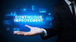 © ra2 studio - Hand of Businessman holding CONTINUOUS IMPROVEMENT inscription, business success concept