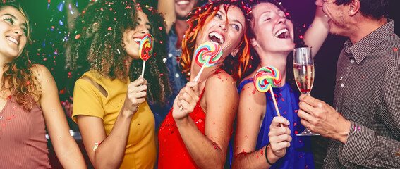 Wall Mural - Happy friends celebrating new year eve drinking champagne in nightclub - Young people having fun dancing with lollipops in disco club - Youth culture entertainment lifestyle and nightlife concept