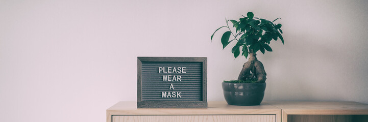 Coronavirus sign with text PLEASE WEAR A MASK upon entering indoor public space retail store panoramic banner. Covid-19 prevention mask obligatory wearing indoors.