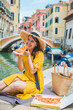 © phpetrunina14 - woman sitting on pond with view of venice canal eating pizza