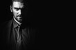 © pridneprovskiy - Portrait of a white Caucasian male brunet in a black classic suit, black shirt and black tie over a black background. Fashionable portrait of an attractive man with dark hair.