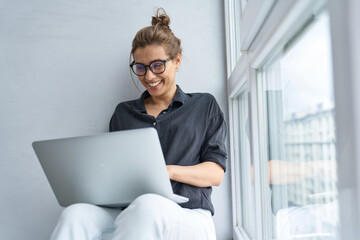 Wall Mural - Happy businesswoman using laptop on window still