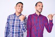© Krakenimages.com - Young gay couple of two men wearing casual clothes smiling with happy face looking and pointing to the side with thumb up.