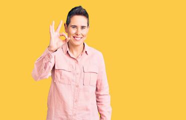 Young woman with short hair wearing casual clothes smiling positive doing ok sign with hand and fingers. successful expression.