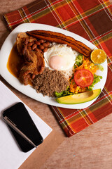 Wall Mural - Bandeja paisa plato tradicional en medellin con carne de cerdo arroz huevo plátano limon tomate aguacate y frijoles rojos