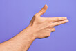 © Krakenimages.com - Hand of caucasian young man showing fingers over isolated purple background gesturing fire gun weapon with fingers, aiming shoot symbol