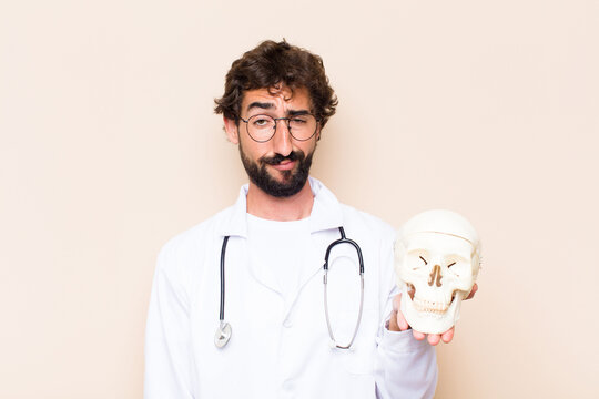 young physician man and a human skull model.