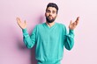 © Krakenimages.com - Young handsome man with beard wearing casual sweater clueless and confused with open arms, no idea and doubtful face.