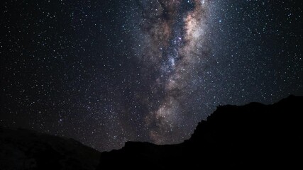 Wall Mural - Time lapse: colorful milky way galaxy and white light stars in solar system night sky, appearance from earth with silhouette mountain range in foreground, static