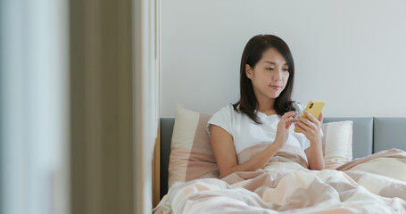 Wall Mural - Woman use of mobile phone on bed