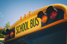 Top Of A Yellow School Bus With Lights And Text. Closeup Against Blue Sky In The Fall. Back To School Concept. Copy Space.