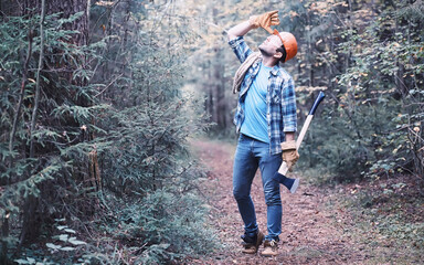 Wall Mural - Male lumberjack in the forest. A professional woodcutter inspects trees for felling.