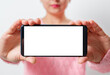 a young woman holds the smartphone horizontally with a white screen with a place for copyspace. on light background