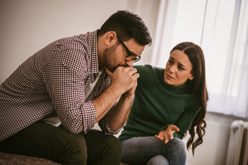 Wall Mural - Man is sad and depressed, his wife is consoling him.