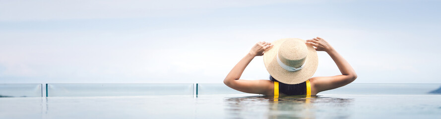 Rear view of asian woman relax at pool resort with outdoor panorama sea view