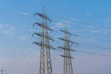 Group silhouette of transmission towers - power tower, electricity pylon, steel lattice tower - at sunset in Humble, Texas, US. Texture high voltage pillar, overhead power line, industrial background