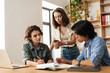 © Drobot Dean - Image of colleagues discussing project while working with laptops