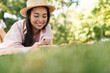 Image of happy asian girl using mobile phone while lying in park