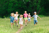 Fototapeta Las - Kids, children running on meadow in summer's sunlight. Look happy, cheerful with sincere bright emotions. Cute caucasian boys and girls. Concept of childhood, happiness, movement, family and summer.