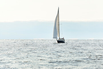 Blue sloop rigged yacht sailing in an open Baltic sea on a clear day, close-up. Riga bay, Latvia. Cruise, sport, recreation, leisure activity concepts