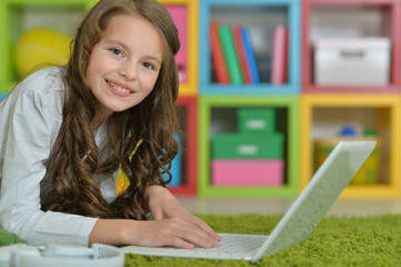 Portrait of cute girl using laptop on floor