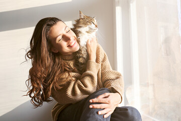 Charismatic young woman playing with her adorable cat.