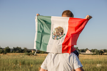 Young boy holding flag of Mexico. 