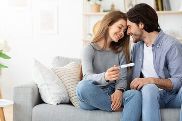 Married couple bonding and holding positive pregnancy test